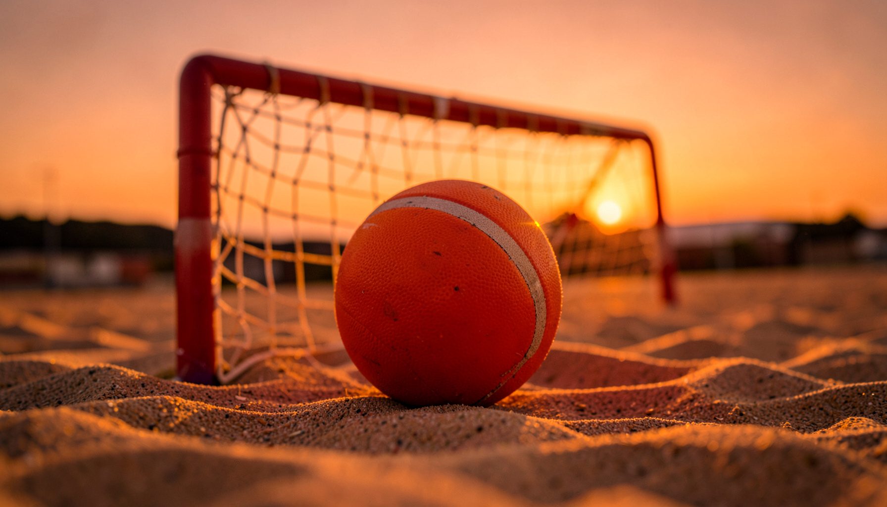 Gün batımında turuncu gökyüzü altında kum sahada voleybol filesi; sıcak ve enerjik bir atmosfer